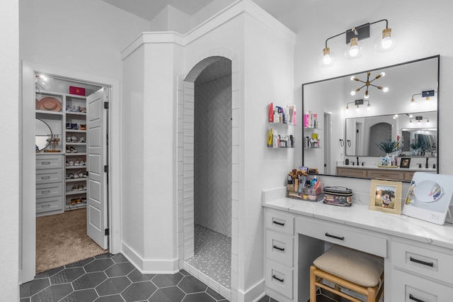 full bath featuring walk in shower, a walk in closet, tile patterned flooring, vanity, and baseboards