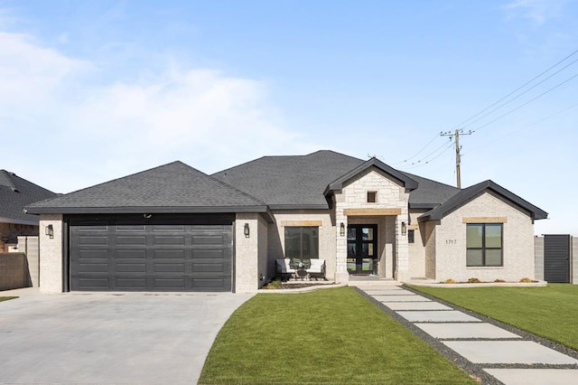 view of front of house featuring a garage, a shingled roof, a front yard, and concrete driveway