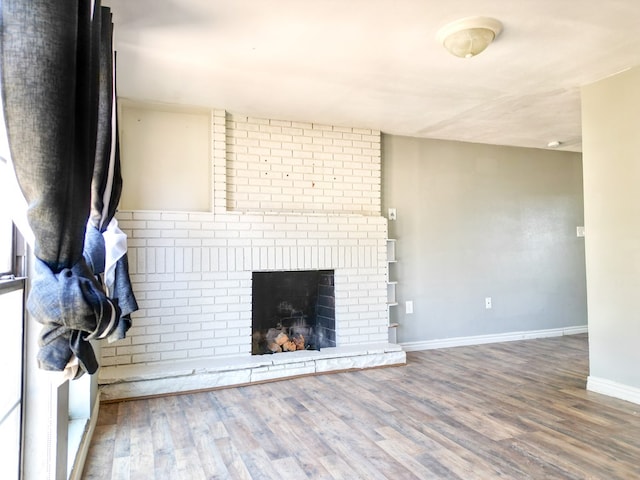 1431 S Alleghaney Ave, Odessa, TX 79761 - unfurnished living room with wood finished floors, baseboards, and a brick fireplace