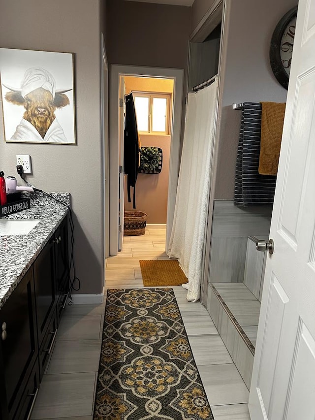 full bath with baseboards, wood finished floors, and vanity