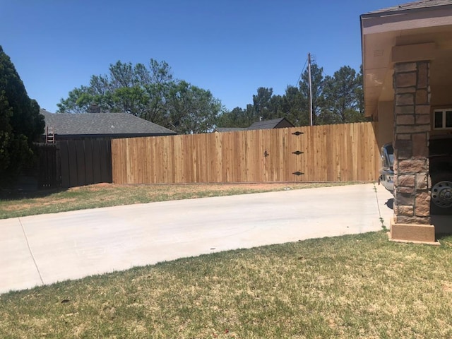 view of yard featuring fence, a patio area, and concrete driveway