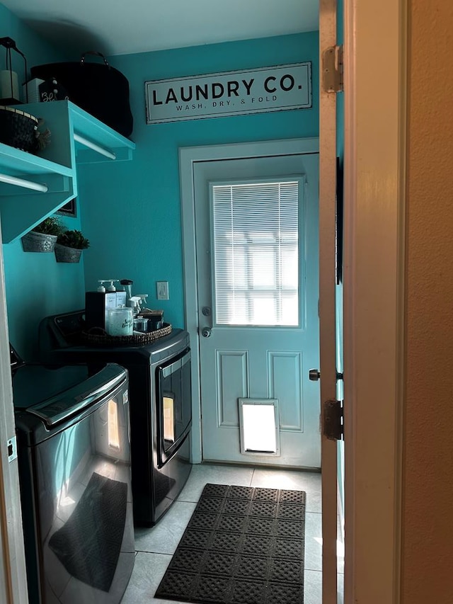 clothes washing area with washing machine and dryer and light tile patterned flooring