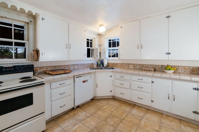 603 N 11th St, Alpine, TX 79830 - kitchen featuring white appliances, decorative backsplash, white cabinetry, lofted ceiling, and tile counters