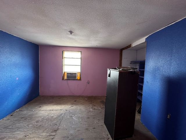 empty room featuring cooling unit, a textured ceiling, and a textured wall