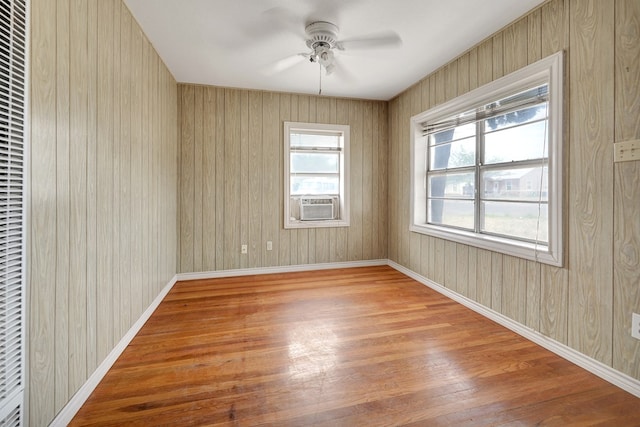 empty room with wood finished floors, ceiling fan, a heating unit, baseboards, and cooling unit