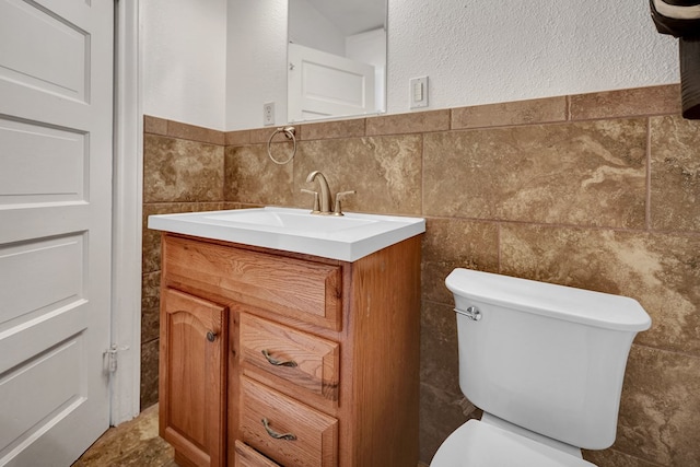bathroom featuring tile walls, toilet, and vanity