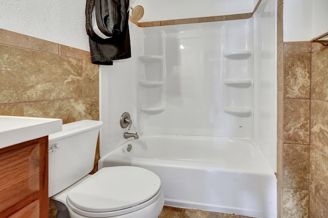 full bath featuring tile walls, toilet, washtub / shower combination, and vanity