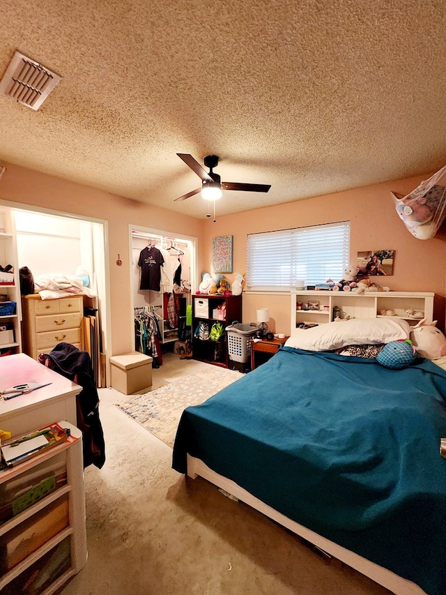 bedroom featuring carpet floors, ceiling fan, a textured ceiling, and visible vents