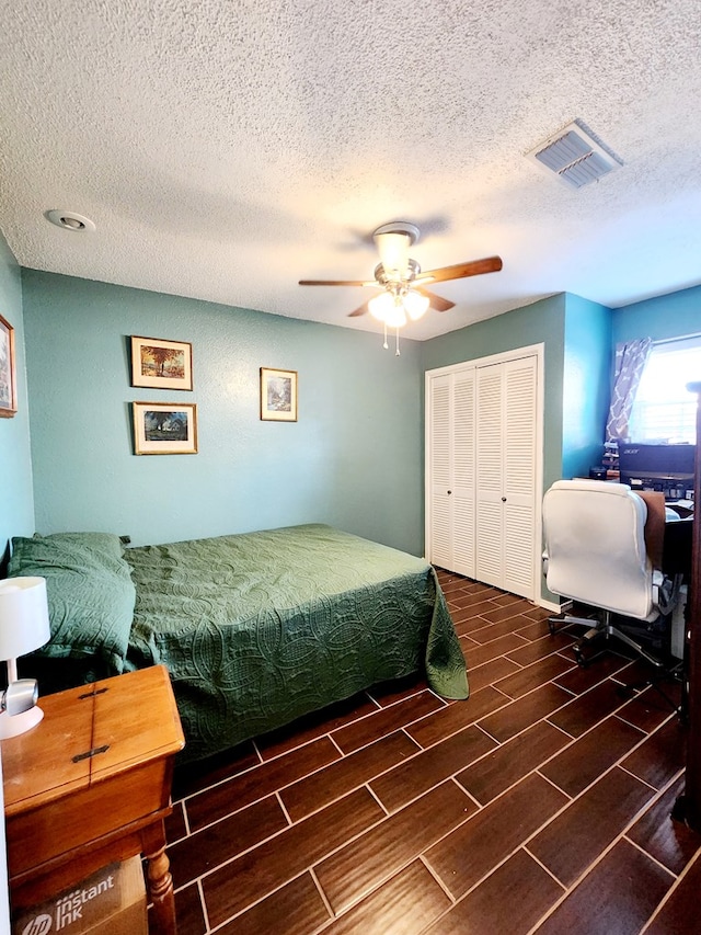 bedroom with a closet, a ceiling fan, a textured ceiling, and visible vents