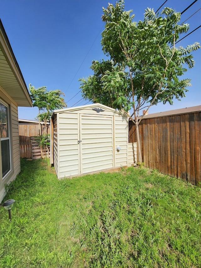view of yard featuring a fenced backyard, an outbuilding, and a shed