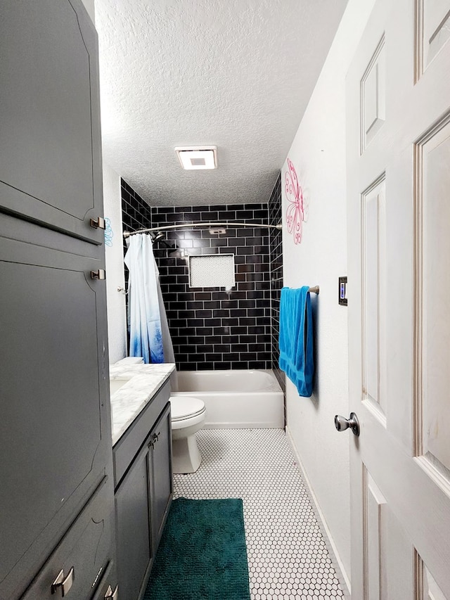 full bath featuring a textured ceiling, tile patterned floors, baseboards, vanity, and toilet