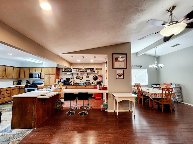 kitchen featuring dark wood-style flooring, light countertops, brown cabinetry, stainless steel appliances, and vaulted ceiling