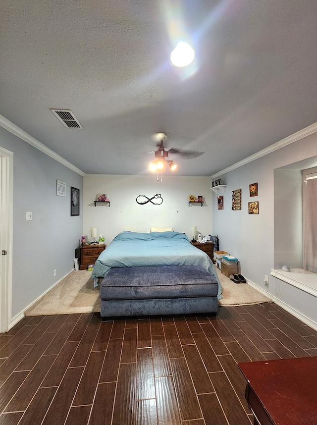 bedroom featuring crown molding, baseboards, visible vents, and wood finished floors