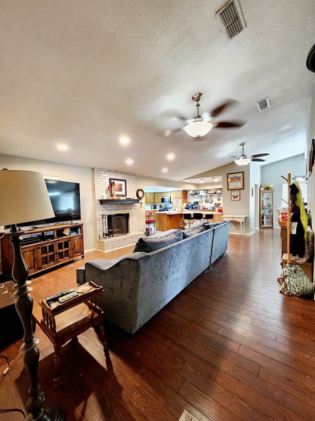living room featuring visible vents, a textured ceiling, ceiling fan, and dark wood-style floors