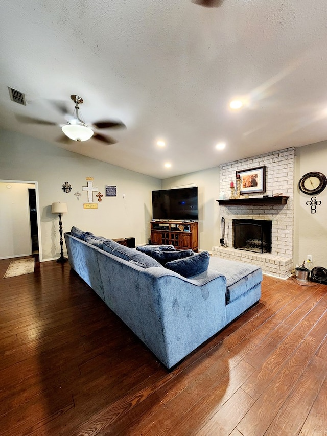 living room featuring visible vents, a brick fireplace, ceiling fan, a textured ceiling, and hardwood / wood-style flooring