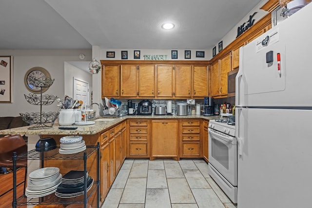 1306 Douglas Dr, Odessa, TX 79762 - kitchen with white appliances, a sink, brown cabinetry, a peninsula, and light stone counters
