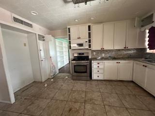 kitchen with open shelves, tile patterned flooring, gas range, white microwave, and visible vents