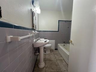 bathroom with tile walls, toilet, tile patterned floors, and a bath
