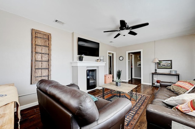 living room with ceiling fan and dark wood-type flooring