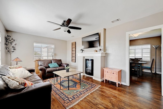 living room with ceiling fan and dark wood-type flooring