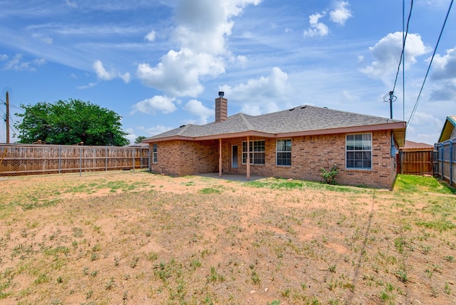 8625 Harvard Ave, Odessa, TX 79765 - back of house with a chimney, a fenced backyard, brick siding, and a shingled roof
