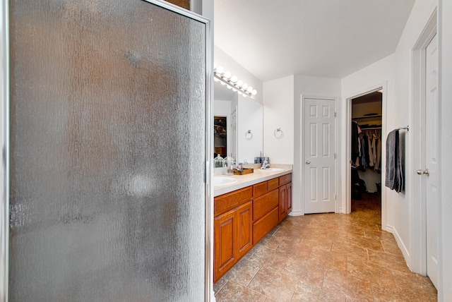 8625 Harvard Ave, Odessa, TX 79765 - full bathroom featuring a tile shower, a spacious closet, double vanity, and stone finish floors