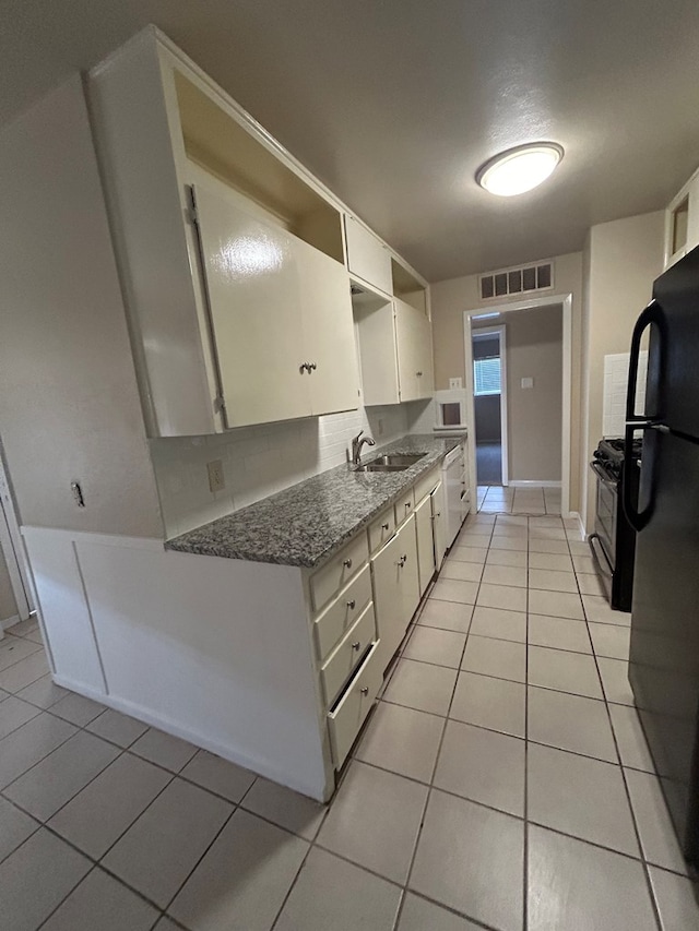 1712 Nabors Ln, Odessa, TX 79761 - kitchen with light tile patterned flooring, freestanding refrigerator, white cabinets, and a sink