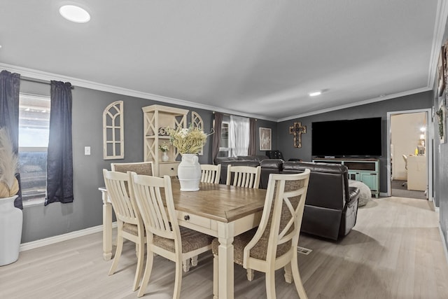 dining room featuring light wood finished floors, baseboards, and crown molding