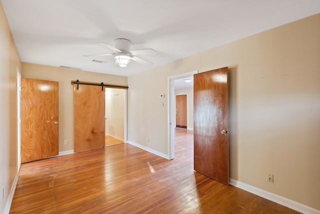 401 E Sul Ross Ave, Alpine, TX 79830 - unfurnished bedroom with wood finished floors, a barn door, baseboards, and a ceiling fan
