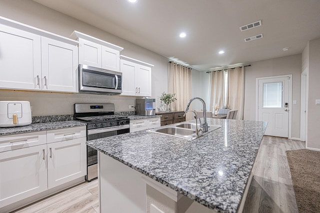 6205 Globe Life Ct, Odessa, TX 79762 - kitchen with stainless steel appliances, white cabinetry, a kitchen island with sink, light wood-type flooring, and recessed lighting