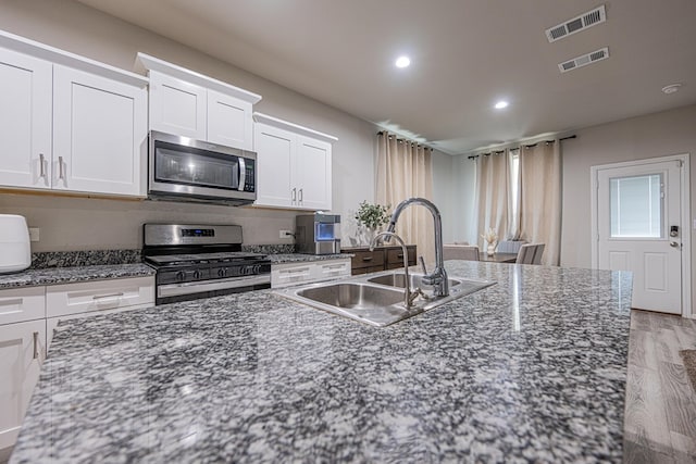 6205 Globe Life Ct, Odessa, TX 79762 - kitchen with stainless steel appliances, light wood-style floors, white cabinets, recessed lighting, and dark stone countertops