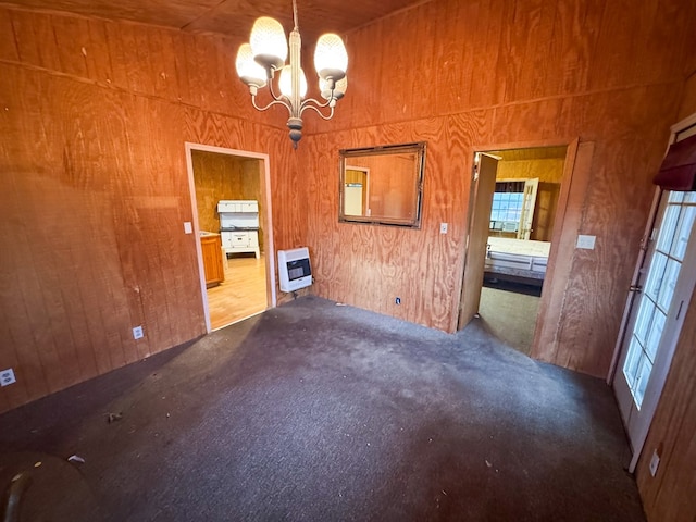 101 Stage Coach Pass, Fort Davis, TX 79734 - unfurnished dining area featuring heating unit, a chandelier, carpet, wood walls, and healthy amount of natural light