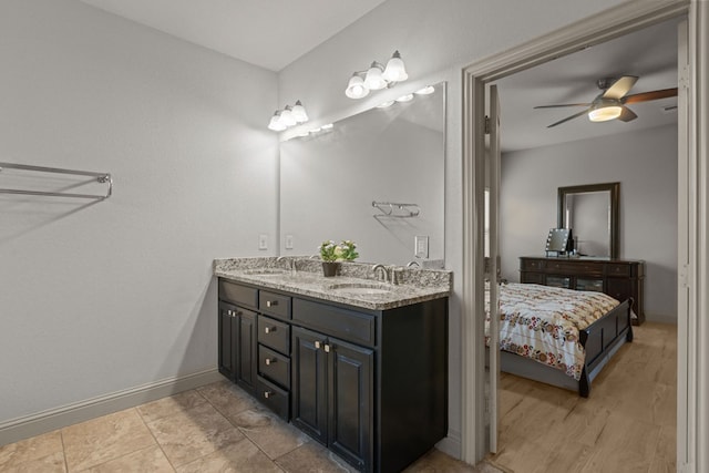 bathroom with a sink, double vanity, baseboards, and ceiling fan