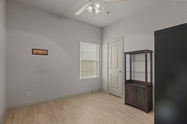 unfurnished room featuring a ceiling fan, baseboards, and light wood-style flooring