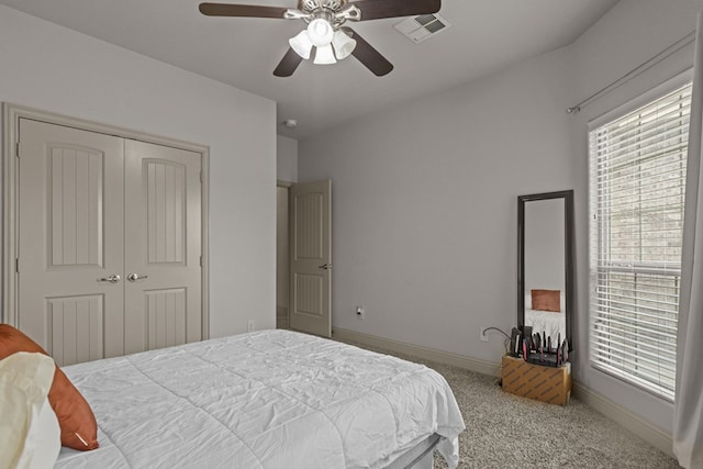 carpeted bedroom featuring baseboards, a closet, visible vents, and a ceiling fan