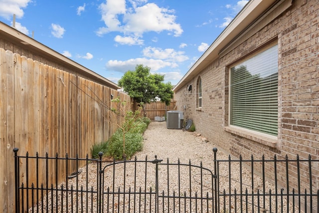 view of yard with a fenced backyard, a gate, and central AC unit