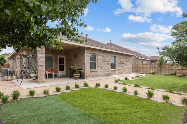 back of house with a lawn, brick siding, fence, cooling unit, and a patio area