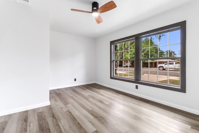 spare room featuring baseboards, a ceiling fan, wood finished floors, and visible vents