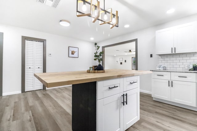 kitchen with decorative backsplash, light wood-style flooring, butcher block counters, and visible vents