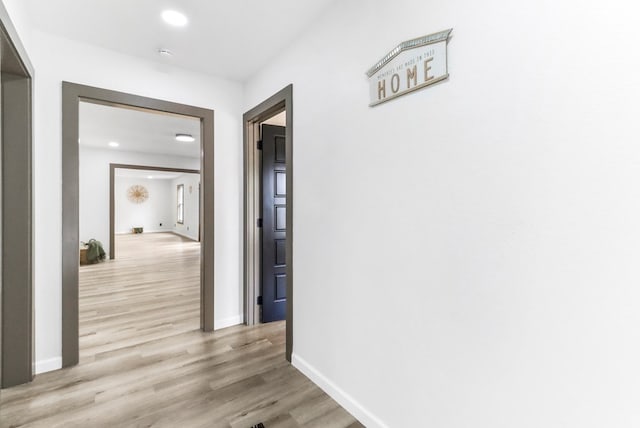 hallway featuring recessed lighting, baseboards, and light wood-style floors