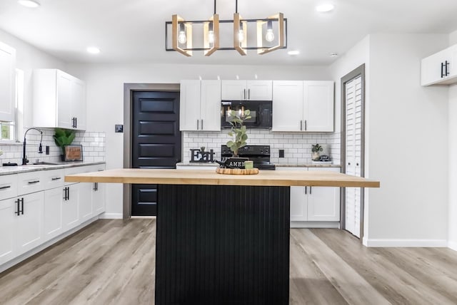 kitchen with wooden counters, a center island, a sink, backsplash, and black appliances