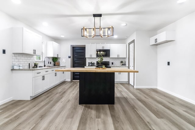 kitchen featuring electric stove, decorative backsplash, butcher block counters, and black microwave