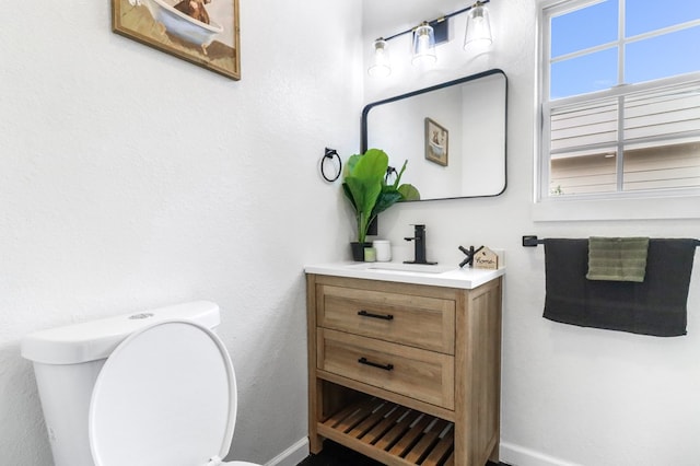half bathroom with toilet, baseboards, and vanity