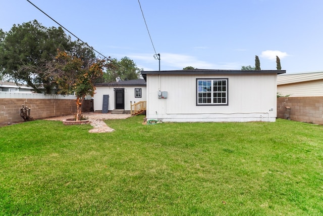 back of house featuring a lawn and a fenced backyard
