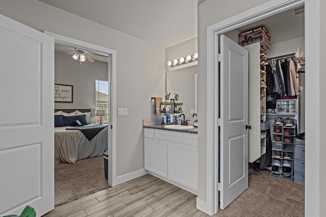 1215 E 93rd St, Odessa, TX 79765 - bathroom featuring wood finished floors, a ceiling fan, vanity, and a walk in closet