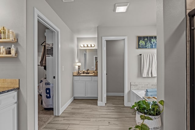 1215 E 93rd St, Odessa, TX 79765 - bathroom featuring vanity, baseboards, wood finished floors, and a garden tub