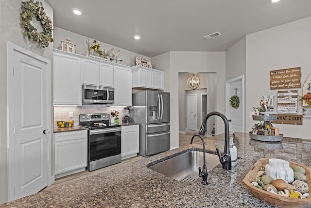 1215 E 93rd St, Odessa, TX 79765 - kitchen featuring stainless steel appliances, a sink, dark stone countertops, backsplash, and white cabinetry