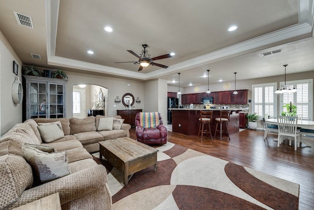 7302 Giotto St, Odessa, TX 79765 - living room with a raised ceiling, crown molding, arched walkways, dark wood-style floors, and ceiling fan