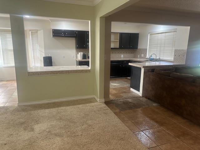 606 NW 14th St, Andrews, TX 79714 - kitchen featuring dark cabinets, ornamental molding, tasteful backsplash, light countertops, and a peninsula