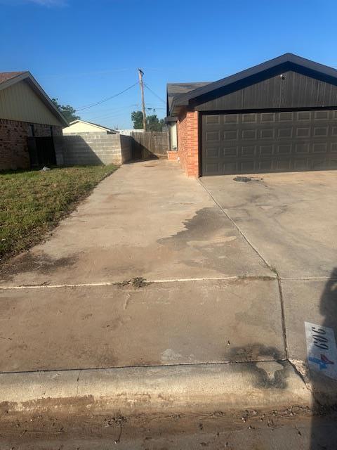 606 NW 14th St, Andrews, TX 79714 - view of property exterior featuring a garage, brick siding, and driveway